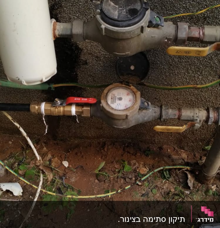 מד מים עם צינורות וברזים מחוברים לקיר